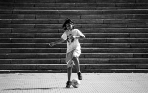 Black and white photo of a child playing soccer on steps in Mar del Plata.