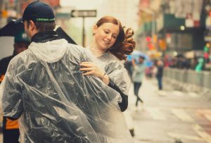 Couple dancing joyfully in the rainwear during a street festival in New York City.