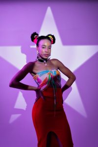 Stylish portrait of a woman in colorful attire with a star backdrop, embodying modern fashion vibes.