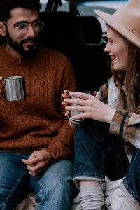 Two friends enjoying a warm coffee conversation outdoors with mugs.