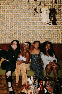 Group of friends celebrating New Year's Eve with festive attire and decor.