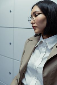 Portrait of a stylish woman in glasses and professional attire indoors.