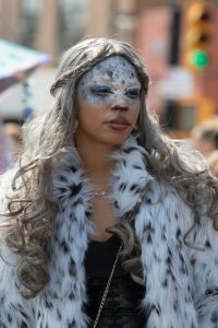 Portrait of a woman in a winter coat with artistic makeup during a street festival in New York City.