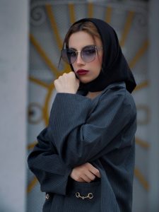 Stylish woman in sunglasses and black hijab, exuding elegance and modern fashion.