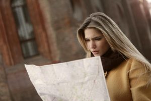 A woman intently reads a map outdoors, highlighting navigation and exploration.