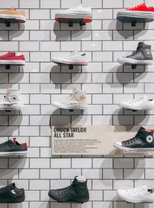 A selection of Chuck Taylor sneakers displayed on a tiled wall in a store.